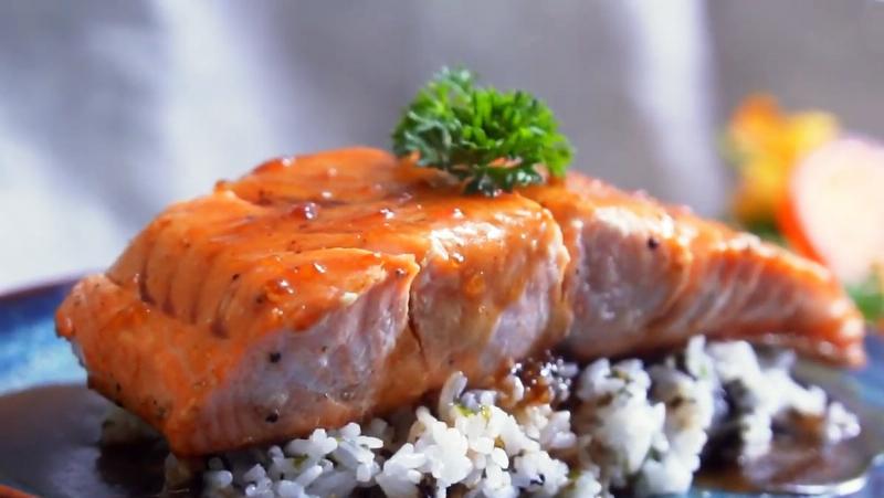 Hình ảnh miếng cá hồi đang được áp chảo trên chảo nóng, mặt da vàng giòn hấp dẫn.